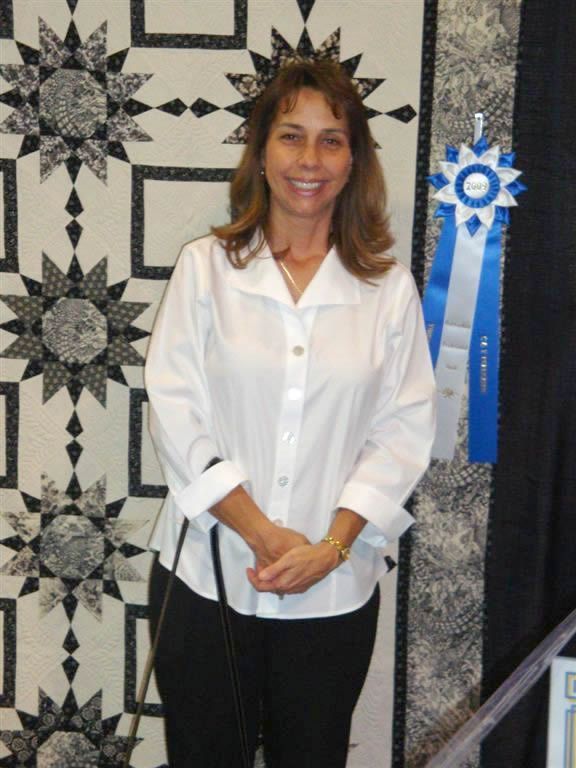 Cindy Seitz-Krug smiling and standing in front of her winning quilt Sew Long Sally